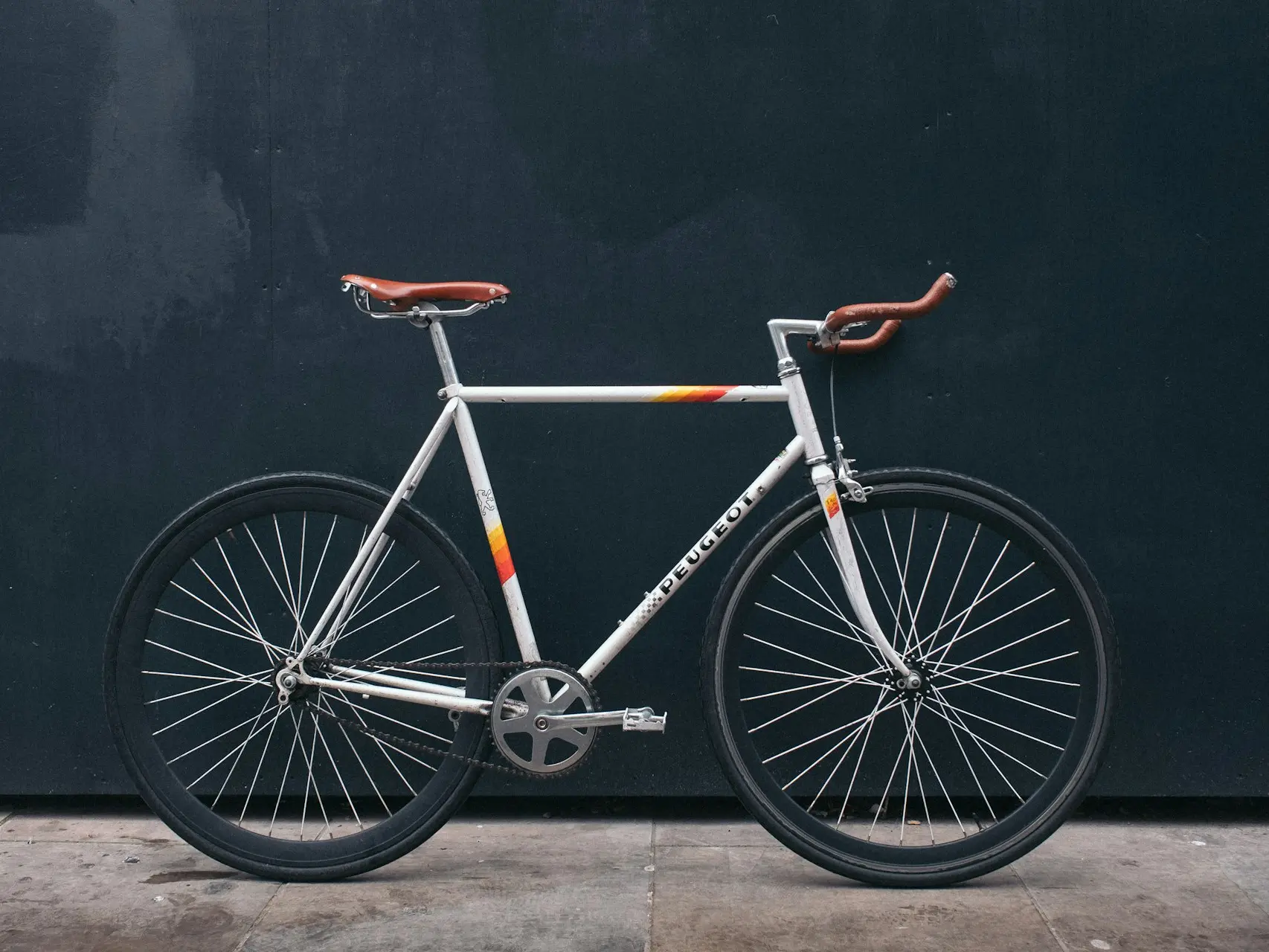 gray fixie bike leaning on black wall