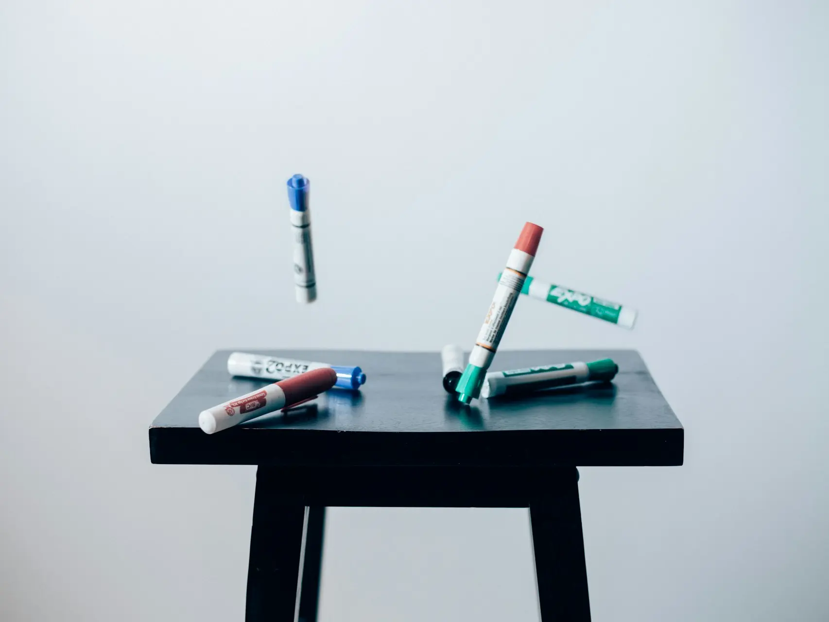 timelaps photo of assorted-color pen on brown wooden saddle stool chair